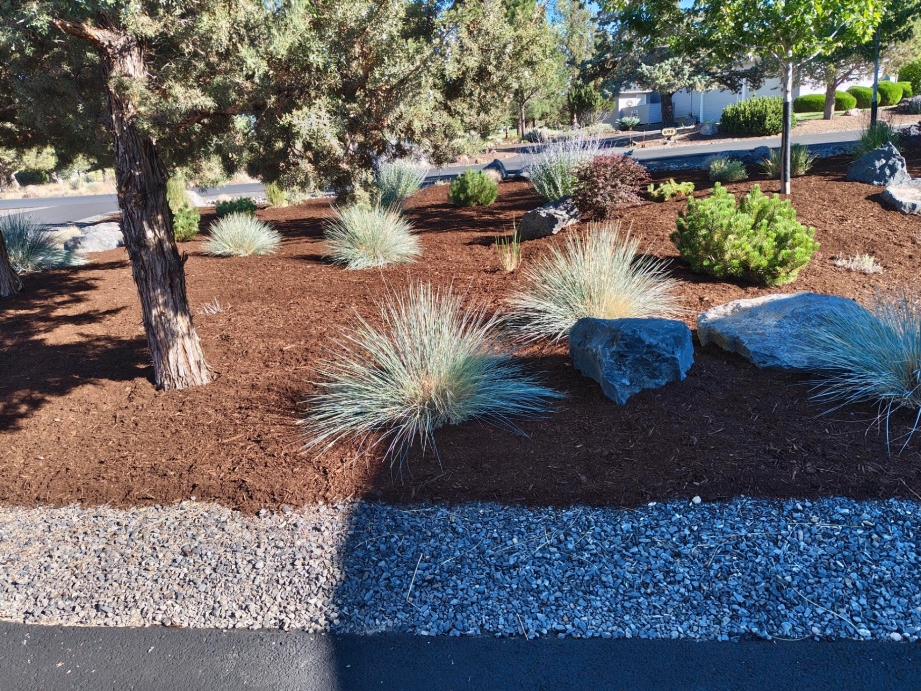 Curb-appeal mulch beds with blue fescue grasses and basalt boulders along a Bend Oregon driveway in Redmond, OR by A1 Lawn & Landscape of Bend